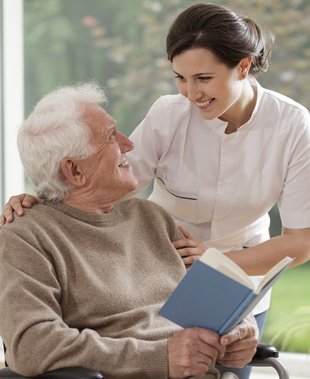 Support worker sharing a cheerful moment with elderly participant reading a book, ThriveWell Care respite and in-home support Melbourne
