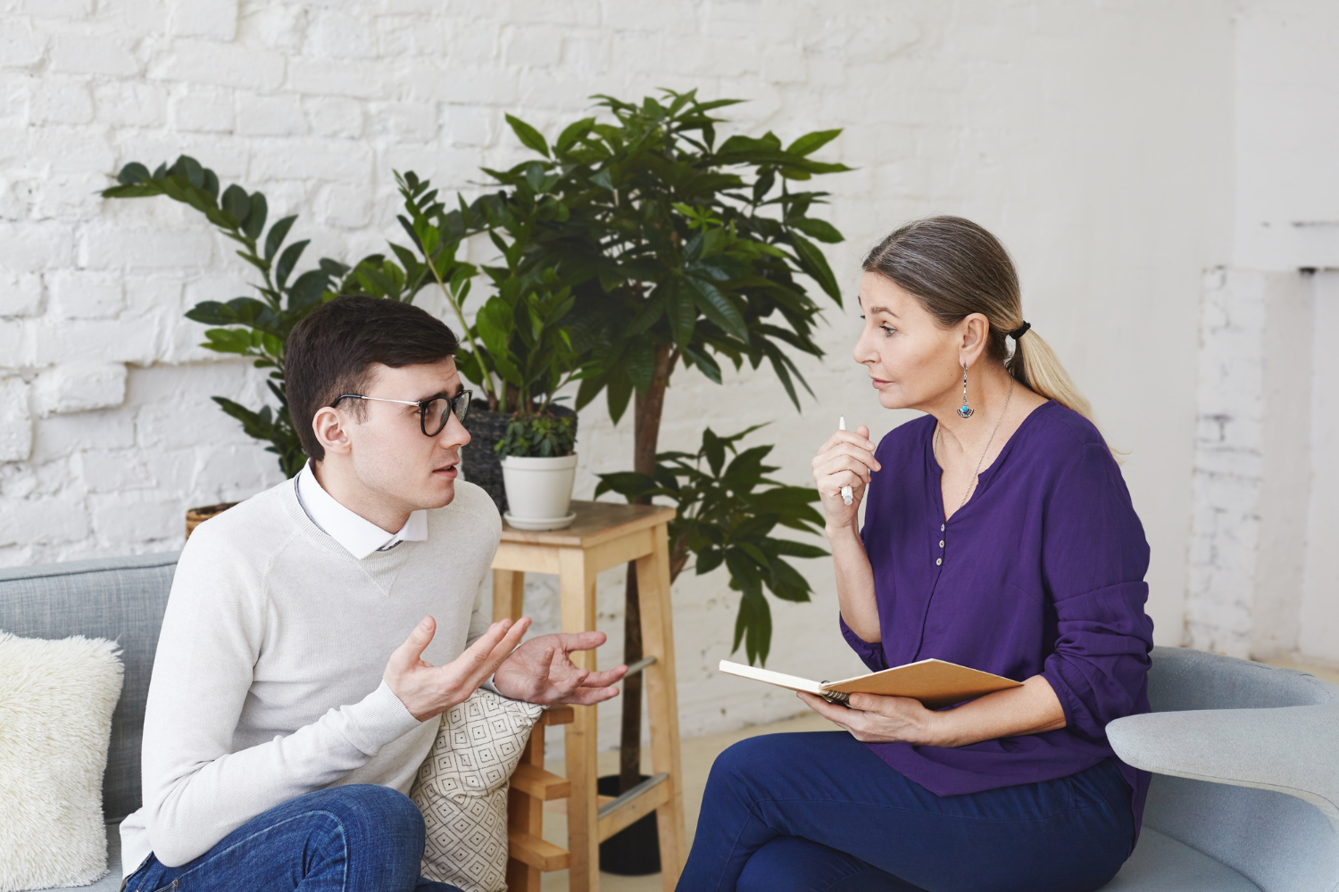 NDIS mental health support worker taking notes while a young male participant shares his recovery goals during a psychosocial support session in Melbourne