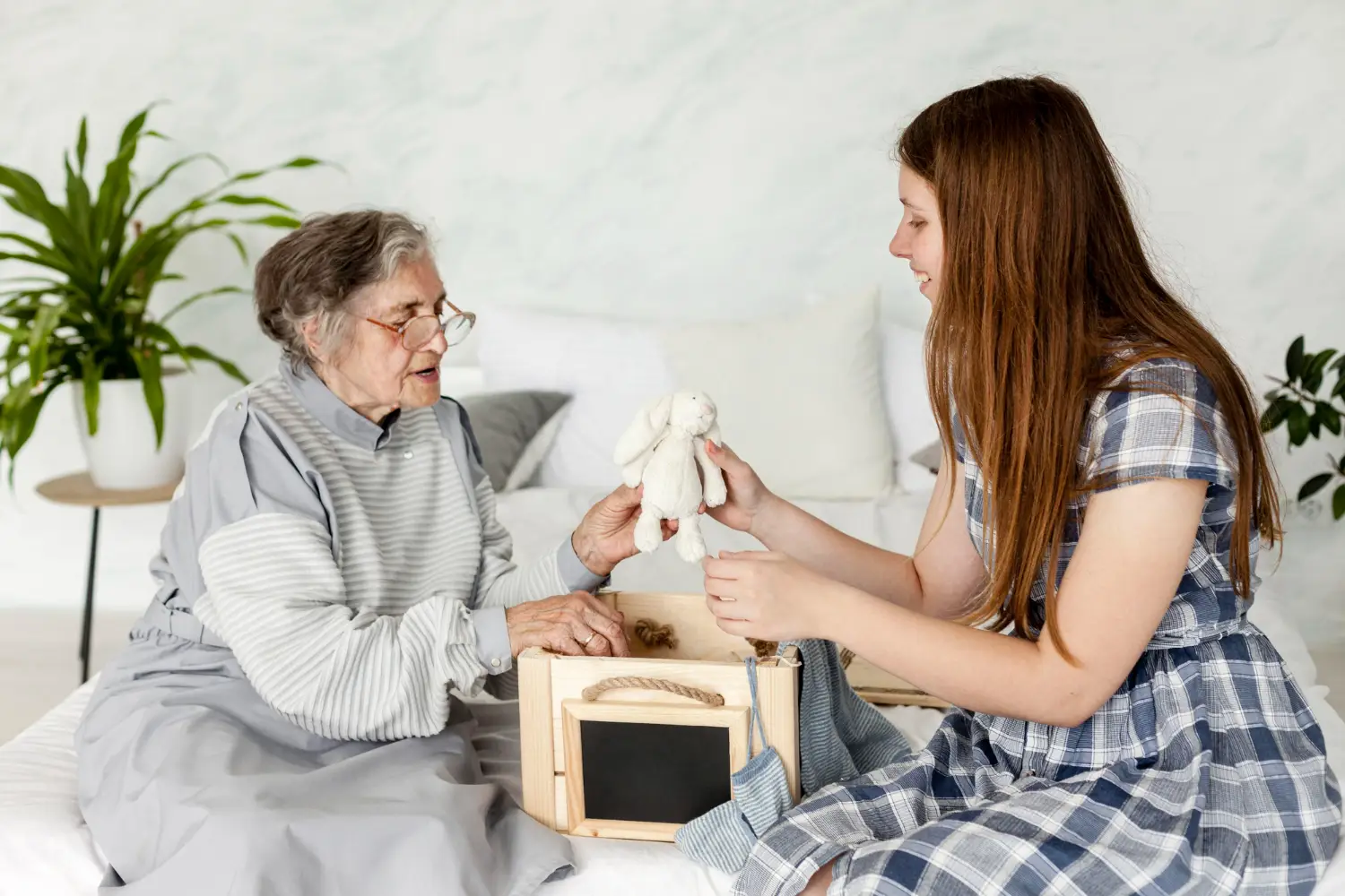 NDIS support worker engaging an elderly woman with a soft toy during a recreational activity session in a mental health residential home in Melbourne