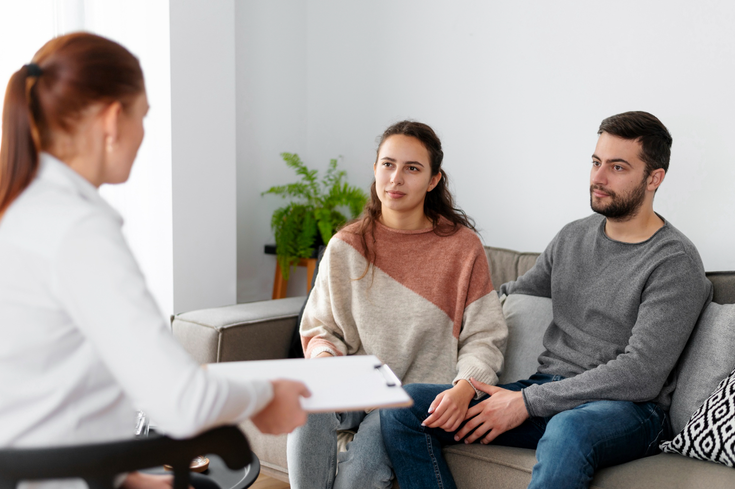 NDIS support worker presenting a care plan on a clipboard to a young couple during a disability support planning consultation at home in Melbourne