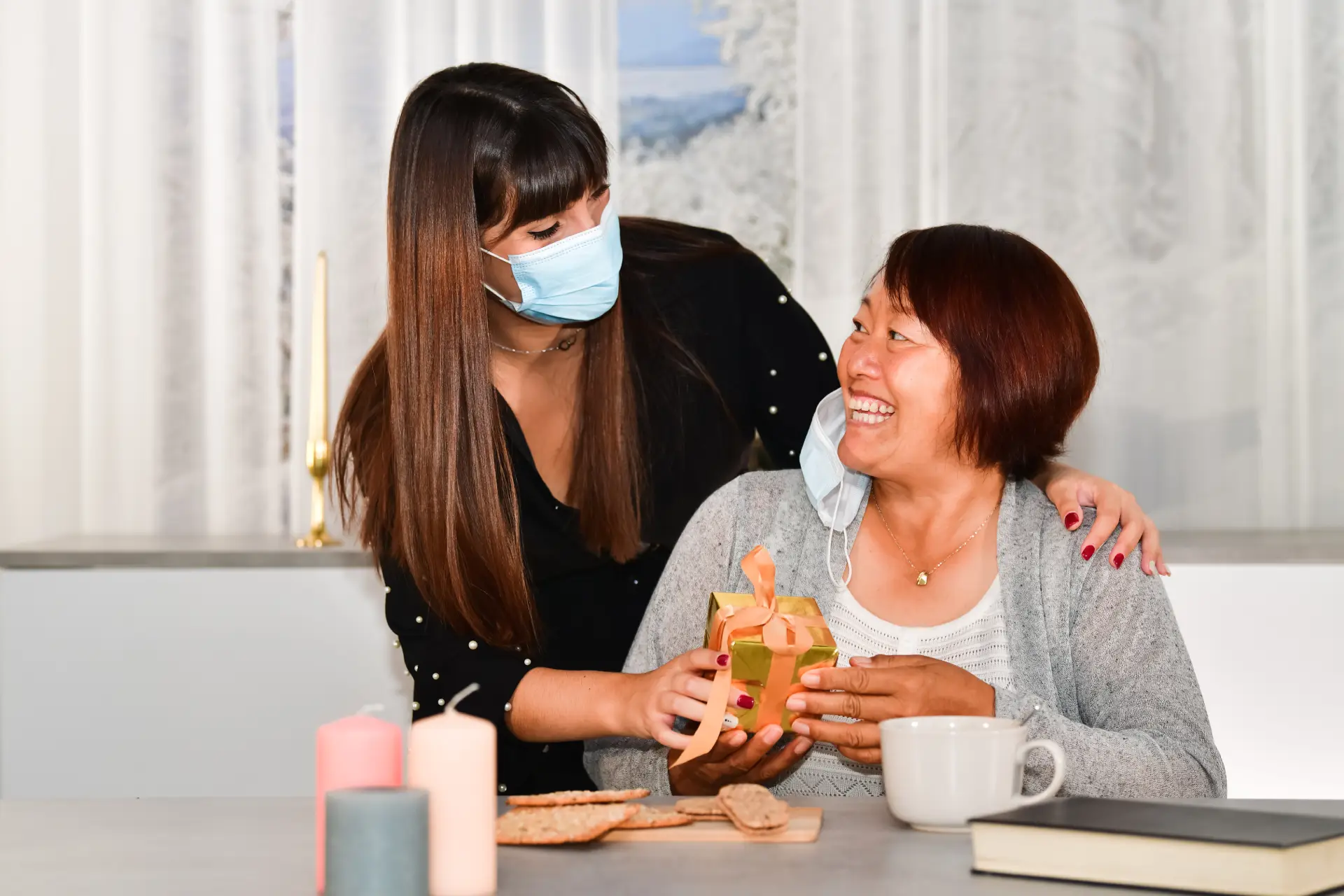 NDIS support worker caring for elderly disability participant with a gift at home in Melbourne